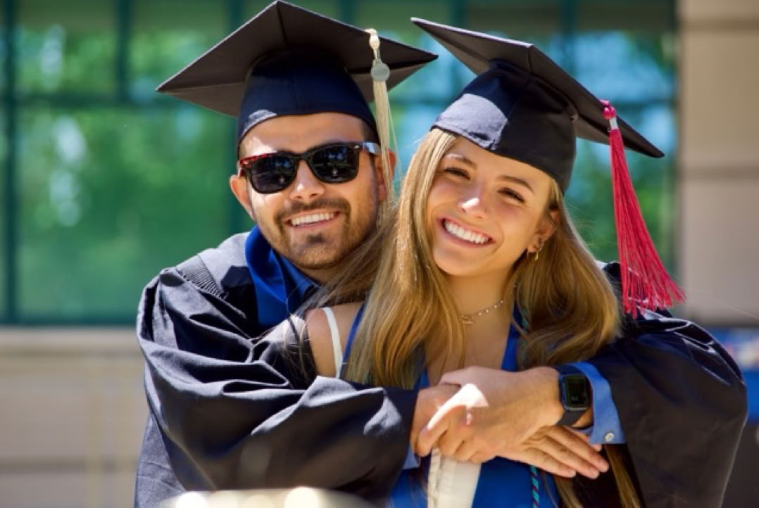 Photo of a man and woman both wearing graduation gowns and hats